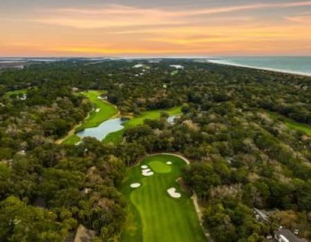 Aerial view of golf course with beach in the background